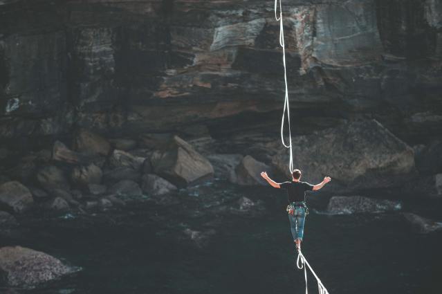 Image of a man on a tightrope walking across a chasm